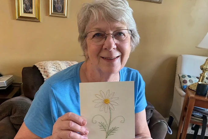 Marion S. tenant sa première marguerite brodée sur papier