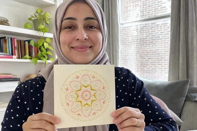 Claudine F. tenant son mandala brodé sur papier